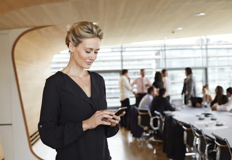 Women stands in boardroom looking at phone